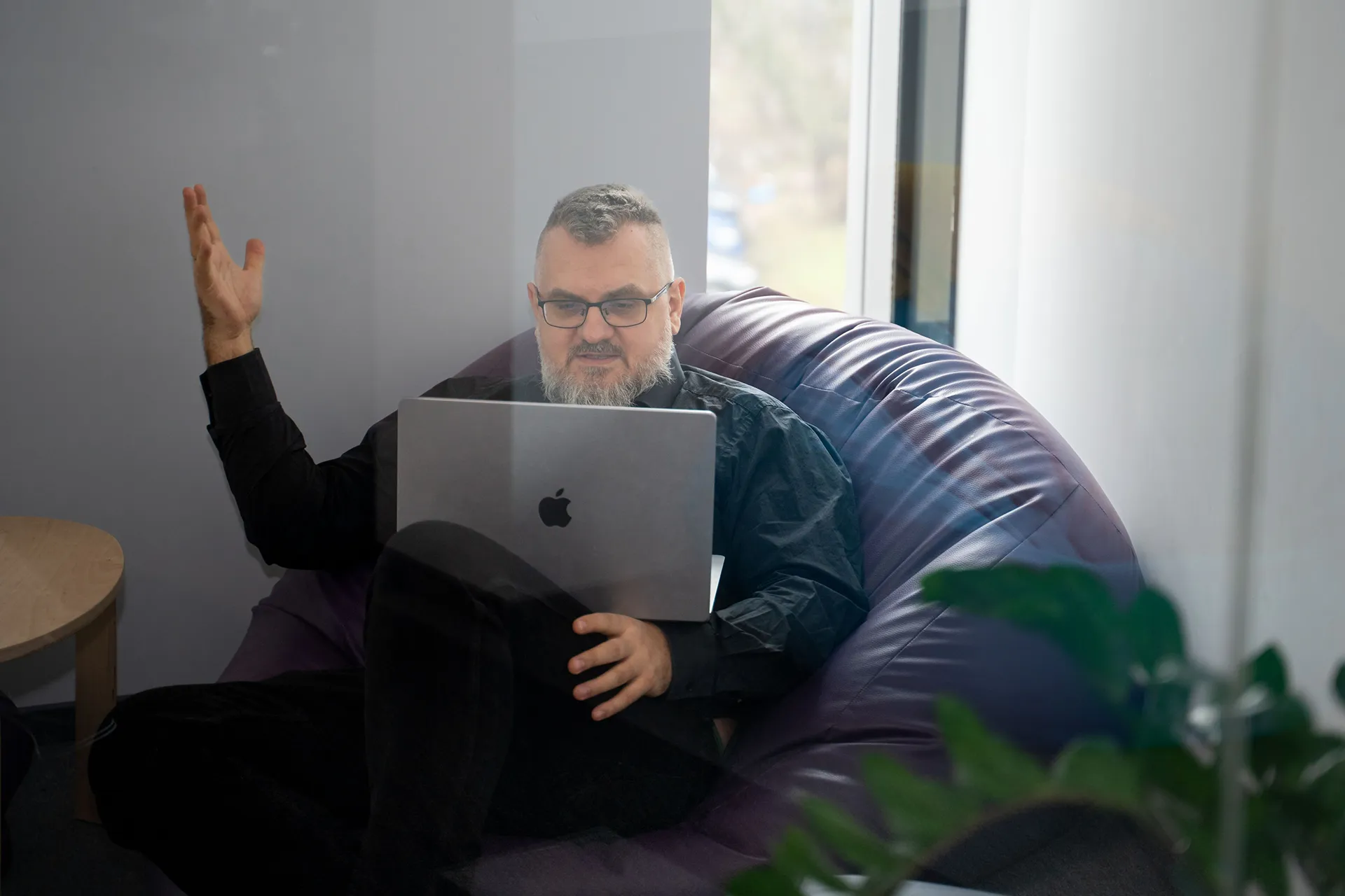 Three people in an office sit and stand around a laptop.